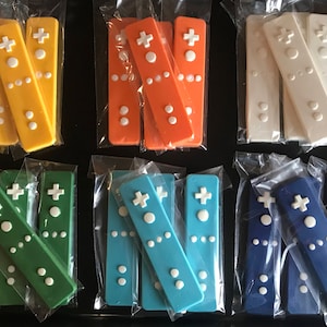 May include: Six sets of colorful plastic Wii remote controllers, each set featuring three controllers in different shades of blue, green, orange, white, and yellow. The controllers are arranged in rows on a black surface.