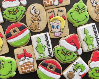 Puede incluir: Una colección de galletas de Navidad decoradas con varios diseños con temática del Grinch, incluyendo la cara del Grinch, la silueta del Grinch, Cindy Lou Who, Max el perro y un adorno navideño. Algunas galletas tienen el texto "Merry Grinchmas" escrito en ellas.