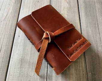 May include: A brown leather journal with a leather strap and knot closure. The journal is personalised with the text "Most loved Name" and "Love Alex Kaitlin & Cole".
