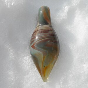 May include: A teardrop-shaped glass pendant with swirling patterns of brown, white, and gray.