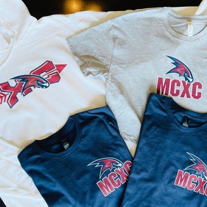 May include: Three shirts with a red and blue falcon logo. The white hoodie has a red arrow and the text "XFC". The gray t-shirt has the text "MCXC". The navy blue t-shirt has the text "MCXC".