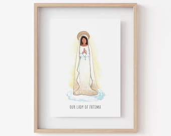 May include: A watercolor illustration of Our Lady of Fatima, a religious figure depicted in a white gown with a blue sash and a halo. The image is framed in a light wood frame.