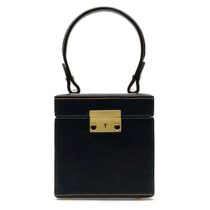 May include: A black, rectangular handbag with a rounded handle. The bag features a gold-colored clasp and stitching. The handle is attached with gold-colored hardware. The bag is designed to be carried by hand.