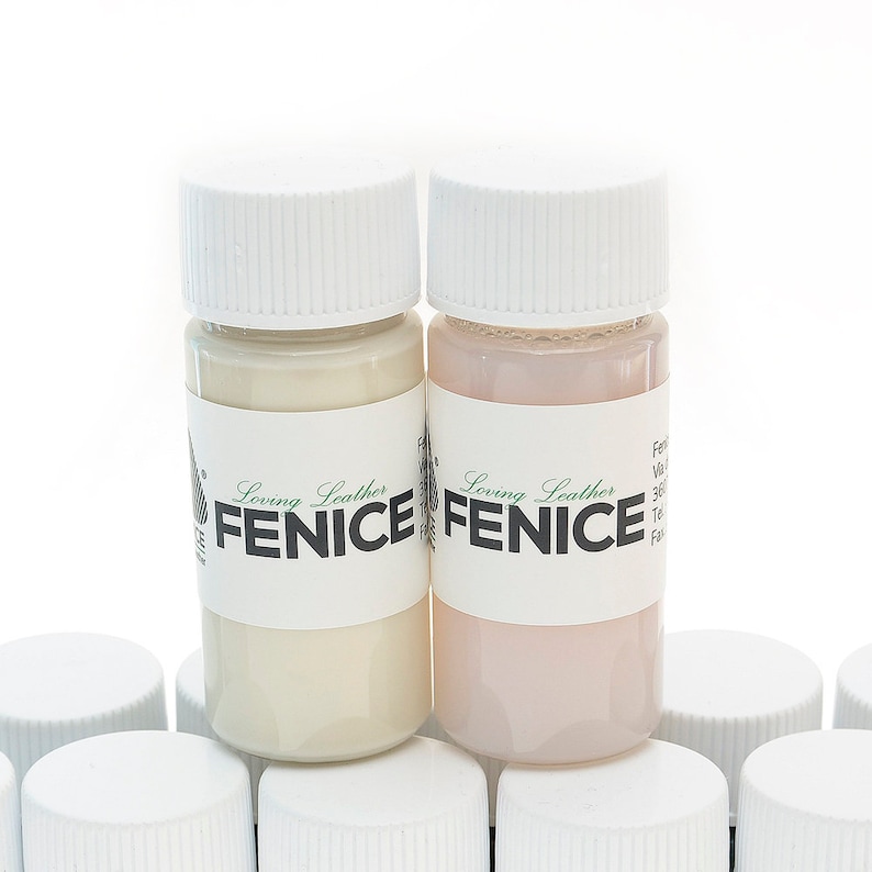 May include: Two small bottles of leather paint with white caps. One bottle contains a cream-colored paint, and the other contains a light pink paint. The bottles have labels with the text "Loving Leather FENICE".