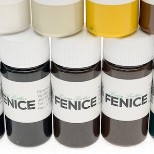 May include: Close-up of several small bottles of leather dye in various colors. The bottles have white lids and labels with the word "FENICE" and "Loving Leather" printed on them. The colors include black, brown, and yellow.