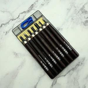 May include: A set of wood carving tools in a clear plastic case. The tools have dark brown wooden handles with silver-colored metal accents. The set includes a blue rubber band and text in Japanese.