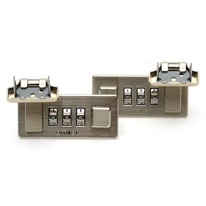 Op de afbeelding: Twee zilverkleurige combinatiesloten met de merknaam "amiet" op de voorkant. Elk slot heeft vier cijferwielen en een metalen sluiting. De wijzerplaten tonen de cijfers 1, 0, 0 en 9. De sloten staan tegen een witte achtergrond.