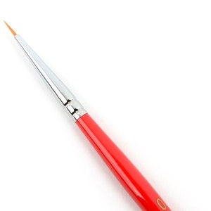 Può includere: Pennello artistico a punta fine con manico rosso brillante e ghiera argentata. Il pennello ha una punta a setole lunga, sottile e arancione, ideale per la pittura di dettaglio e la nail art. Il manico è liscio e lucido.