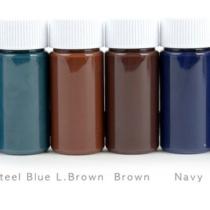 May include: Six small bottles of paint in a row, each with a white cap. The colors are blue, steel blue, light brown, brown, navy, and black. The names of the colors are printed below each bottle.