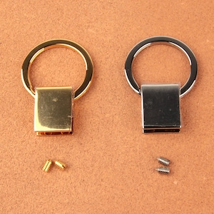 Pu&ograve; includere: Due anelli metallici, uno dorato e uno argentato, con chiusure rettangolari. Sono incluse piccole viti. Probabilmente utilizzati per la fabbricazione di borse o altri progetti artigianali.