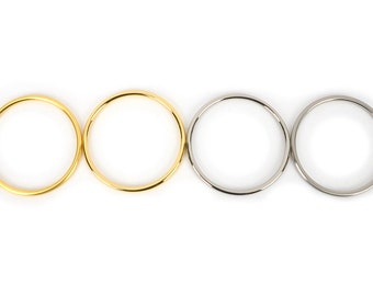 May include: Four metal rings in gold and silver tones are displayed against a white background. The rings are circular and have a smooth, polished finish. The gold rings are on the left, and the silver rings are on the right.