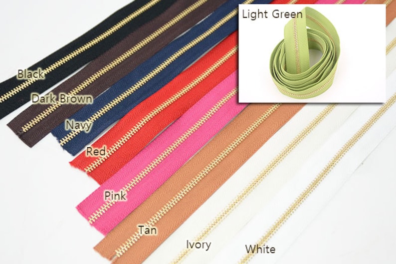 Puede incluir: Una variedad de cremalleras de colores con dientes dorados. Los colores incluyen negro, marr&oacute;n oscuro, azul marino, rojo, rosa, beige, marfil y blanco. Una inserci&oacute;n separada muestra una cremallera verde claro.