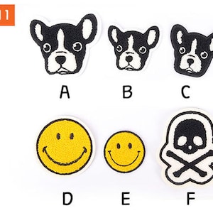 May include: A collection of six embroidered patches. Three patches feature a black and white French bulldog face. Two yellow smiley face patches and a black and white skull and crossbones patch are also included. The text "OPTION 1" is in the upper left corner.