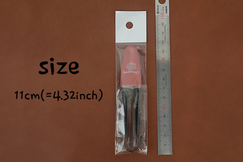 K&ouml;nnte beinhalten: Ein rosa Kosmetikpinsel mit dem Text "SJC SAMJOUNG" in einer transparenten Plastikverpackung. Die Gr&ouml;&szlig;e betr&auml;gt 11 cm. Ein Metalllineal befindet sich neben dem Pinsel.