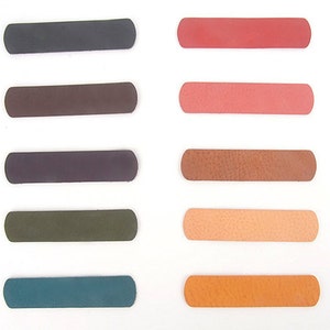 May include: A collection of rectangular leather swatches in various colors, including shades of gray, brown, red, and orange. The swatches are arranged on a white background, showcasing their different textures and hues. Ideal for craft projects.