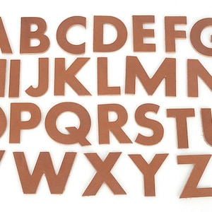 May include: Full set of uppercase letters, A through Z, cut from brown leather. The letters are arranged on a white background. Each letter is a solid, blocky font style, perfect for crafting or educational projects.