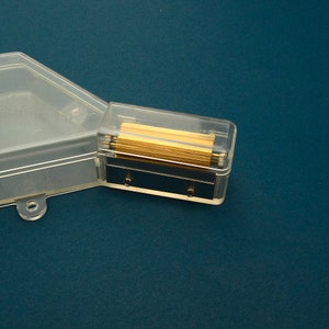 Puede incluir: Un sacapuntas de pl&aacute;stico transparente con un compartimento rectangular de cuchillas doradas. El sacapuntas tiene una tapa de pl&aacute;stico transparente y una base azul oscuro.