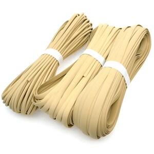 May include: Three bundles of beige-colored flat rubber strips, each secured with a white band. The strips are neatly coiled, showcasing a smooth, matte texture. The arrangement suggests a craft or DIY supply, possibly for edging or trim.