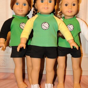 Puede incluir: Tres mu&ntilde;ecas de cabello casta&ntilde;o, cada una con una camiseta verde con un gr&aacute;fico de voleibol en el pecho y pantalones cortos negros. La mu&ntilde;eca de la izquierda tiene mangas negras, la del centro mangas amarillas y la de la derecha mangas blancas. La mu&ntilde;eca central lleva zapatos blancos.