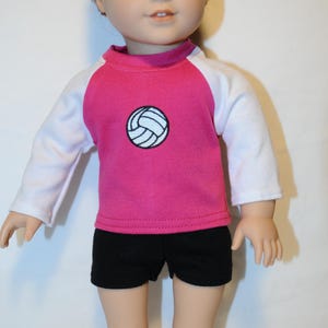 Puede incluir: Una mu&ntilde;eca de cabello casta&ntilde;o rojizo viste una camiseta de manga larga con torso rosa y mangas blancas, con un gr&aacute;fico de voleibol blanco centrado y contornos negros, combinado con pantalones cortos negros lisos hasta el muslo.
