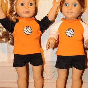 Puede incluir: Dos mu&ntilde;ecas de piel clara y cabello largo con ropa deportiva. La mu&ntilde;eca de la izquierda lleva una camiseta naranja con mangas negras y pantalones cortos negros. La mu&ntilde;eca de la derecha lleva una camiseta naranja con mangas blancas y pantalones cortos negros. Ambas camisetas tienen un gr&aacute;fico de voleibol.