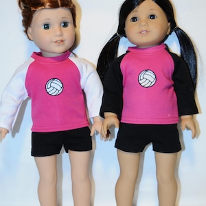 Puede incluir: Dos mu&ntilde;ecas de pie una al lado de la otra. La mu&ntilde;eca de la izquierda tiene el pelo casta&ntilde;o rojizo en un mo&ntilde;o y viste una camiseta rosa con mangas blancas y pantalones cortos negros. La mu&ntilde;eca de la derecha tiene el pelo negro en coletas y viste una camiseta rosa con mangas negras y pantalones cortos negros. Ambas camisetas tienen un peque&ntilde;o gr&aacute;fico de voleibol blanco en el pecho.