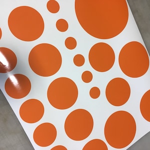 May include: A white background with orange circles of varying sizes. The circles are arranged in a random pattern.