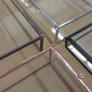 Puede incluir: Tres cajas de exhibici&oacute;n de vidrio con marcos de diferentes colores. Las cajas son de vidrio y tienen marcos de metal. Los marcos son plateados, negros y cobre.