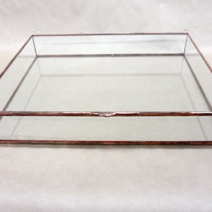 May include: A clear glass display box with a copper frame. The box has a hinged lid and is perfect for displaying small items.