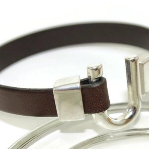 May include: A brown leather bracelet with a silver hook clasp.