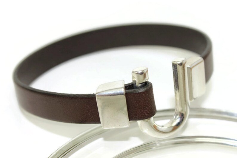 May include: A brown leather bracelet with a silver hook clasp.