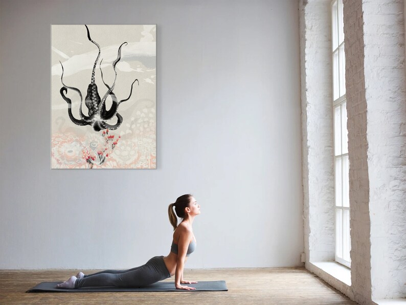 K&ouml;nnte beinhalten: Eine Frau in einem grauen Yoga-Outfit macht eine Kobra-Pose auf einer grauen Yogamatte vor einer wei&szlig;en Wand mit einem schwarz-wei&szlig;en Kraken-Druck, der daran h&auml;ngt. Der Raum hat ein gro&szlig;es Fenster mit wei&szlig;en Ziegeln drumherum.