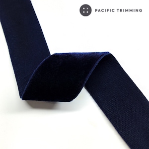 May include: Navy blue velvet ribbon with a slightly textured surface. The ribbon is folded in half and the velvet side is facing up.