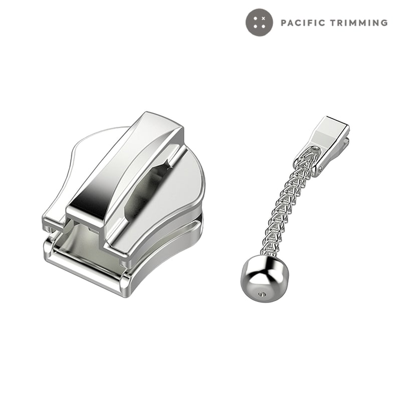 May include: Silver zipper pull with a metal slider and a chain attached to a round metal end piece. The zipper pull is labeled "PACIFIC TRIMMING".
