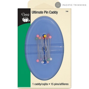 Puede incluir: Un porta agujas de plástico azul con 15 agujas de colores. El porta agujas tiene forma ovalada y tiene un pequeño agujero en el centro. El texto "Ultimate Pin Caddy" está impreso en el embalaje.