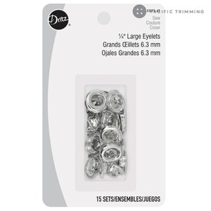 May include: A package of 15 sets of silver 1/4 inch large eyelets, also known as grommets, for sewing projects. The package includes the text "Dritz 33IFIC TRIMMING Sew Couture Coser 1/4" Large Eyelets Grands Œillets 6.3 mm Ojales Grandes 6.3 mm 15 SETS/ENSEMBLES/JUEGOS".