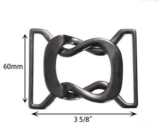 May include: A black metal belt buckle with a unique knot design. The buckle measures 3 5/8 inches wide and 2 3/8 inches tall.