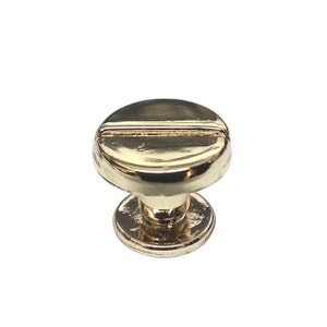 May include: A gold-toned metal screw-style knob with a round top and a base. The top has a single horizontal groove.
