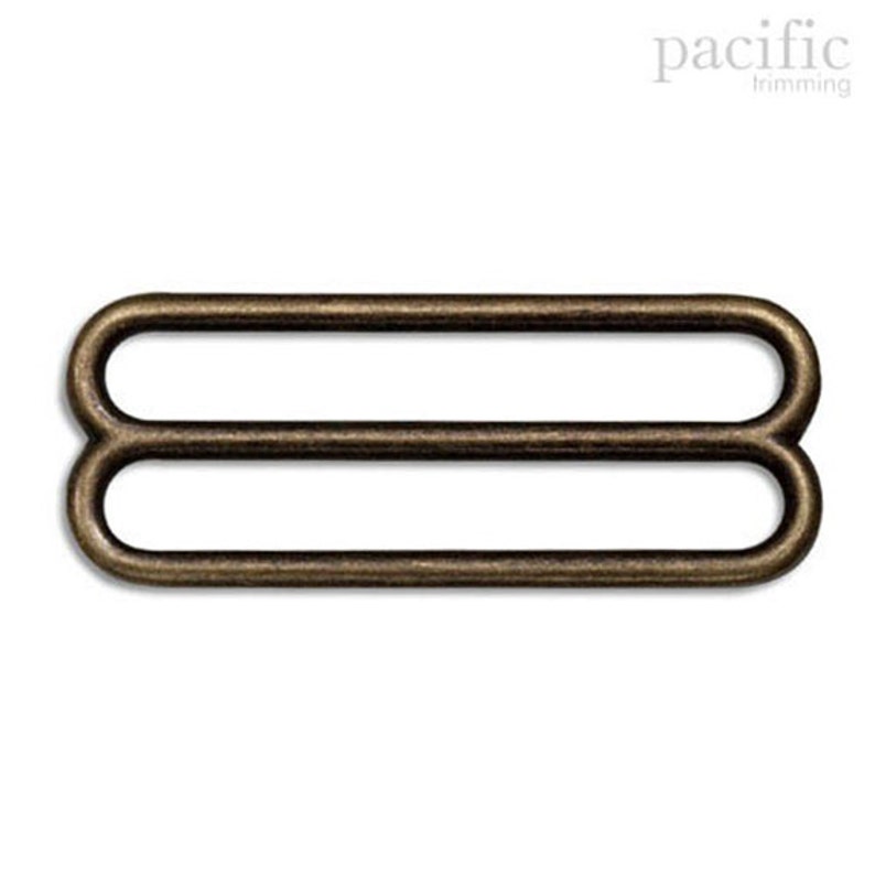 May include: Antique gold metal slider buckle with two loops. This buckle is used for adjusting the length of straps or belts.