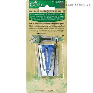 May include: A silver bias tape maker with a blue plastic guide. The tool is designed to make bias tape for sewing projects. The packaging includes instructions in English, French, Spanish, German, and Japanese. Art No. 464/25. Clover.