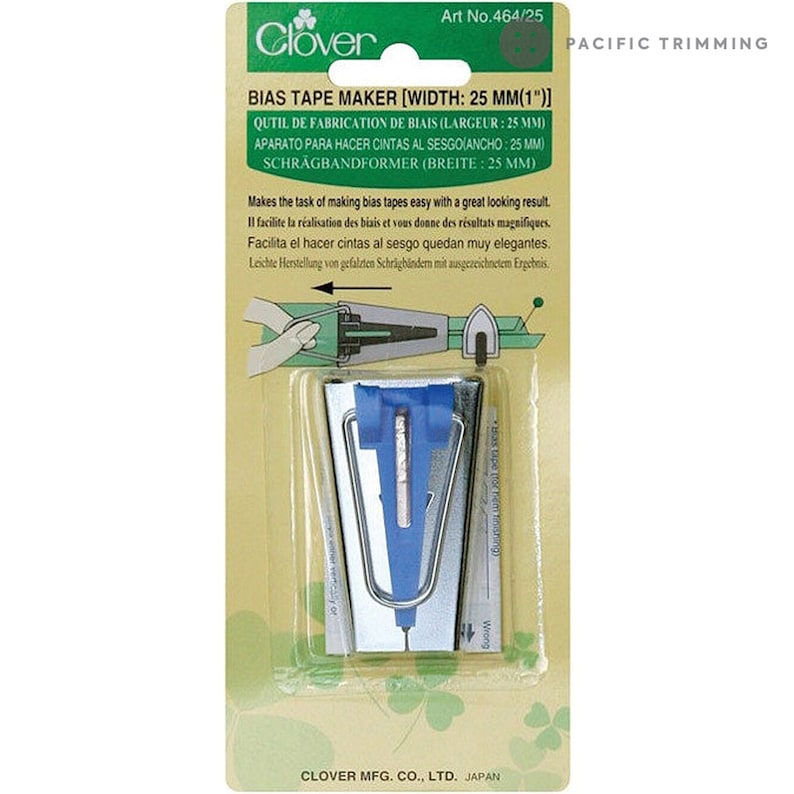May include: A silver bias tape maker with a blue plastic guide. The tool is designed to make bias tape for sewing projects. The packaging includes instructions in English, French, Spanish, German, and Japanese. Art No. 464/25. Clover.