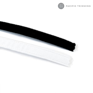May include: Two pieces of black and white trim fabric. The black trim is a velvet fabric and the white trim is a woven fabric.