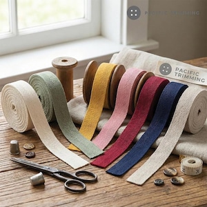 May include: A collection of herringbone cotton twill tape rolls in cream, sage green, yellow, pink, burgundy, and navy blue. The set includes a pair of metal scissors, two metal thimbles, several brown buttons, and a small white measuring tape.