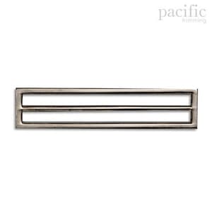 May include: Silver metal buckle with two parallel slots. The buckle is rectangular and has a smooth, polished finish.