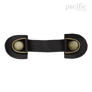 Könnte beinhalten: Schwarzes Lederband mit zwei messingfarbenen D-Ringen und einem Knopfverschluss. Das Band ist etwa 7,5 cm lang.