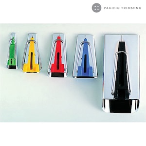 May include: Five seam rippers with different colored handles. The handles are green, yellow, red, blue, and black. The seam rippers are made of metal and have a sharp point. The seam rippers are arranged in a row from left to right. The seam rippers are all the same size. The seam rippers are all made by Pacific Trimming.