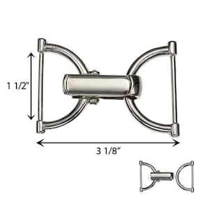 Puede incluir: Una hebilla de metal plateado con dos bucles semicirculares conectados por un mecanismo de cierre central. El herraje mide 3,81 cm de alto y 7,94 cm de ancho, con una vista m&aacute;s peque&ntilde;a y separada de las piezas en la parte inferior derecha.