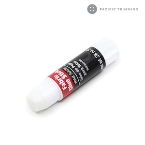 Puede incluir: Un tubo blanco de Fabric Glue Stick, soluble en agua, para telas. El tubo est&aacute; etiquetado con texto negro y fondo rojo. El tubo es de 28 oz.