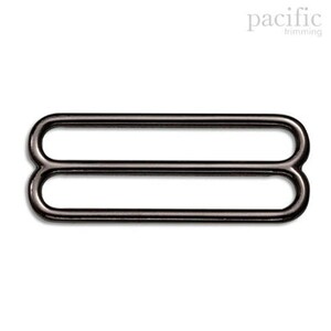 May include: Black metal slider buckle with two loops. This buckle is used for adjusting the length of straps or belts.