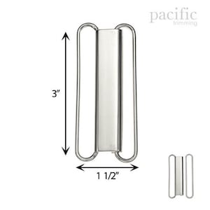 May include: Silver metal slider buckle for clothing, measuring 3 inches in length and 1 1/2 inches in width.